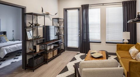 Apartment living room at Westhouse Flats in Fort Worth, TX featuring an open layout, large windows, modern furnishings, and natural light.