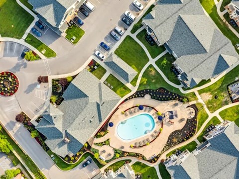 A bird's eye view of a residential area with houses, a swimming pool, and a garden.