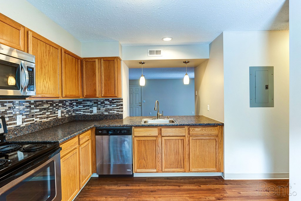 an empty kitchen with wooden cabinets and granite counter tops