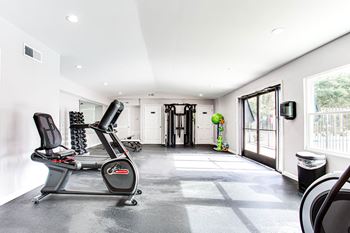 the home gym has a treadmill and a door to the patio