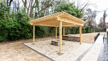 a wooden pavilion with a stone patio and a bench