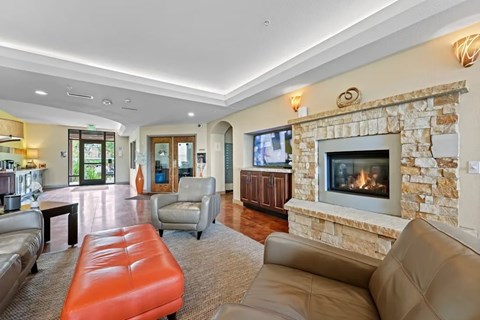 A living room with a stone fireplace and a flat screen TV.