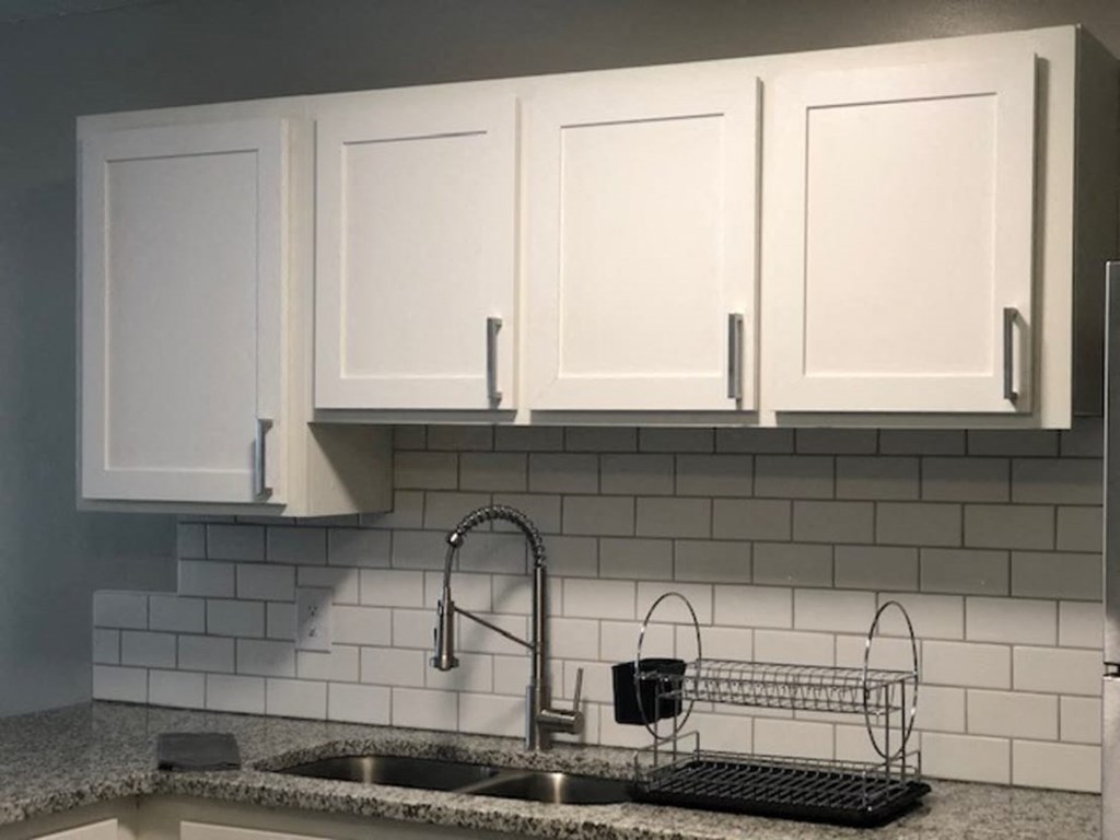 a white kitchen with white cabinets and a sink