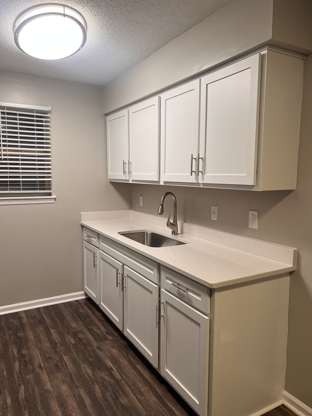 a kitchen with white cabinets and a sink and a window