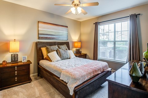 A bedroom with a bed, nightstands, and a ceiling fan.