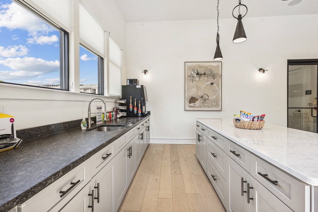 a large kitchen with marble counter tops and white cabinets