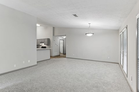 A spacious room with a carpeted floor and a ceiling fan.