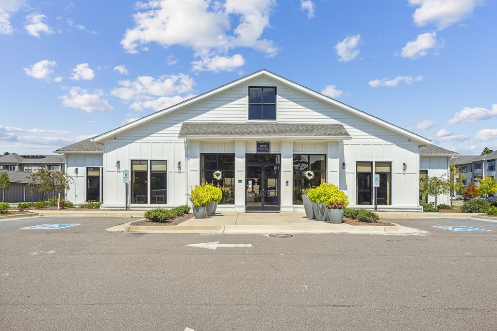 the front of a white building with doors and a parking lot