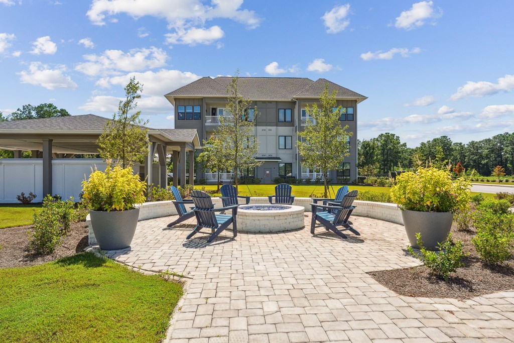 a stone patio with chairs and a fire pit