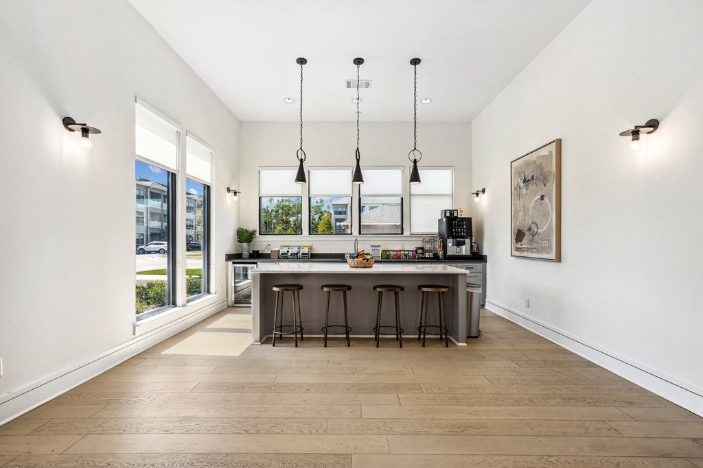 a kitchen with a large island with stools and large windows