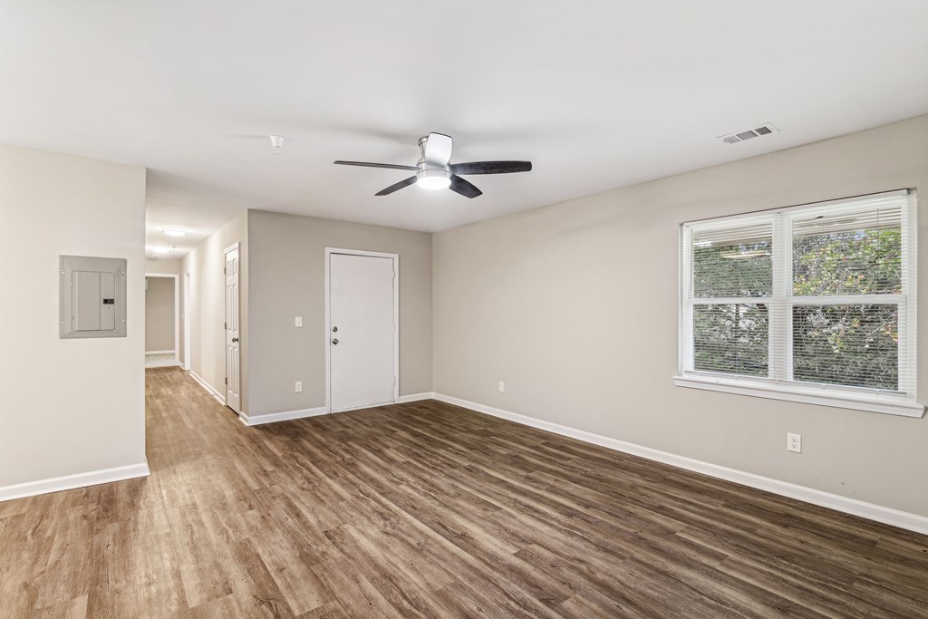 A room with a ceiling fan and a window with a view of trees.