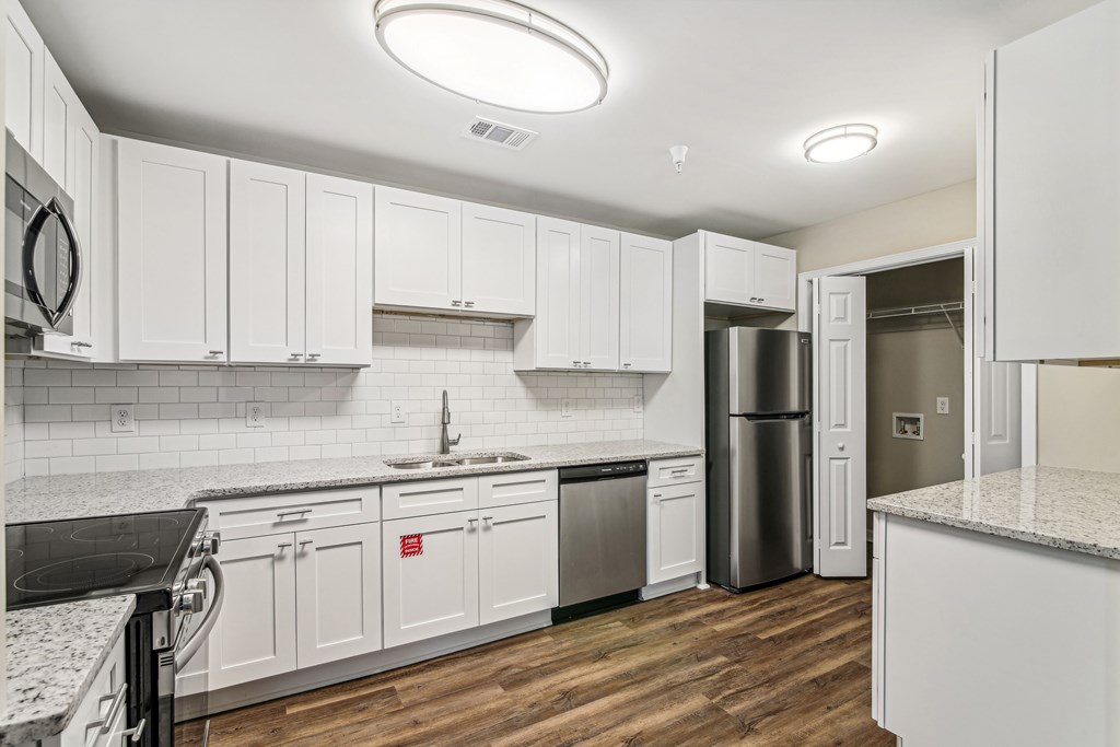 A kitchen with white cabinets and a black counter top.