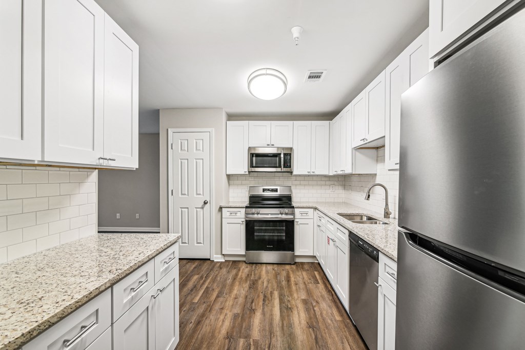 A modern kitchen with white cabinets and stainless steel appliances.