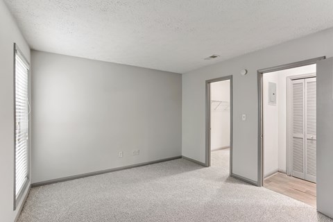 A room with a carpeted floor and a door leading to another room.