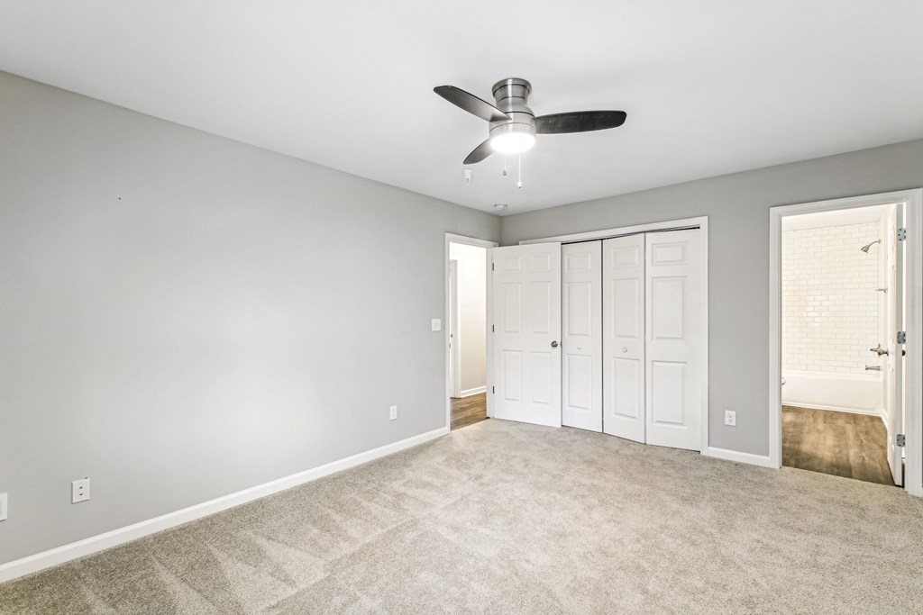 A room with a ceiling fan and carpeted floor.
