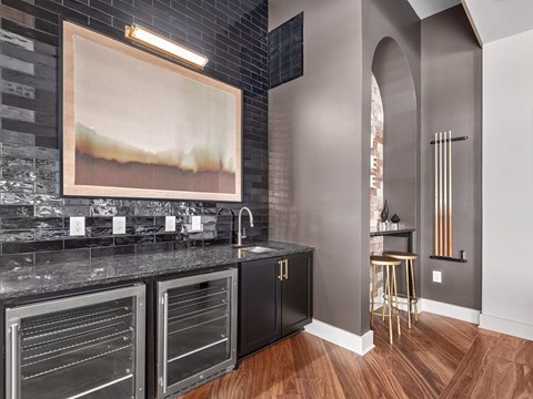 A kitchen with black cabinets and a painting hanging above the counter.