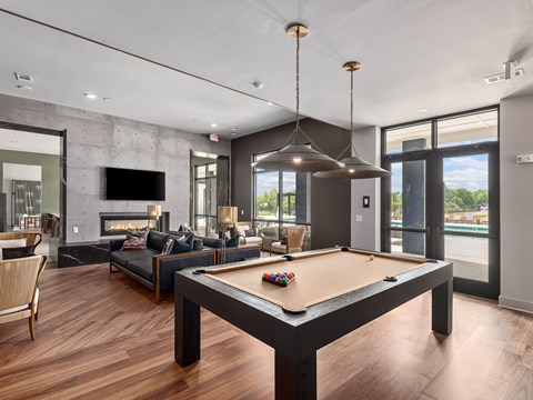 A billiard table is in the middle of a room with a fireplace and a couch.
