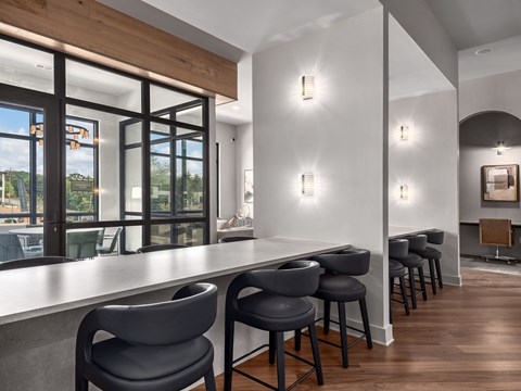 A modern kitchen with a long bar and chairs.