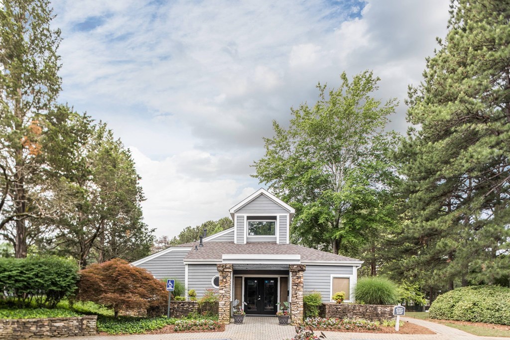 the front of a gray house with a driveway and trees