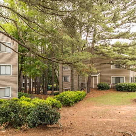 a pathway between two apartment buildings and trees