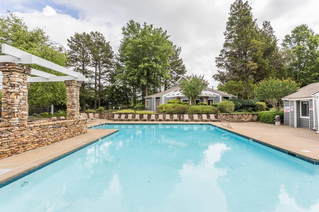 a swimming pool with trees and a house in the background