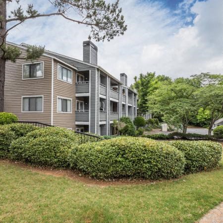 a large apartment building with trees and bushes