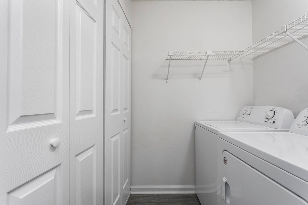 a white laundry room with a washer and dryer and white cabinets