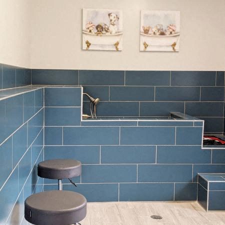 a blue tiled bathroom with a sink and a stool