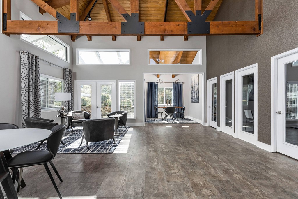 a living room with a vaulted ceiling and a dining room with chairs and tables