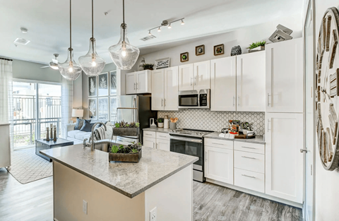 A kitchen with white cabinets and a marble countertop.