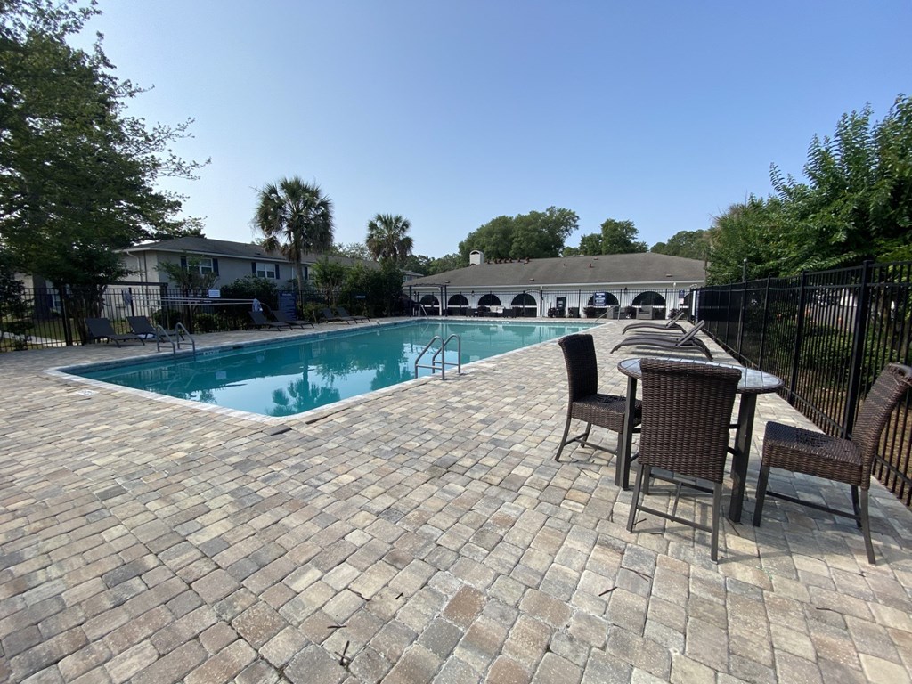 a swimming pool with a patio with chairs and a table at Crescent Place Apartment, Savannah