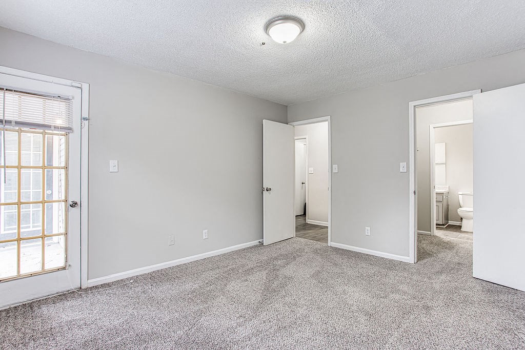 an empty living room with a door to a bathroom