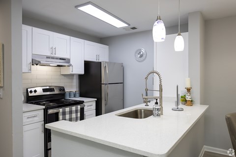 A kitchen with a black refrigerator and white cabinets.