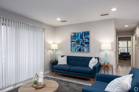 A living room with a blue sofa and a painting on the wall.