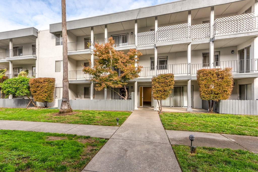 a white apartment building with a sidewalk in front of it