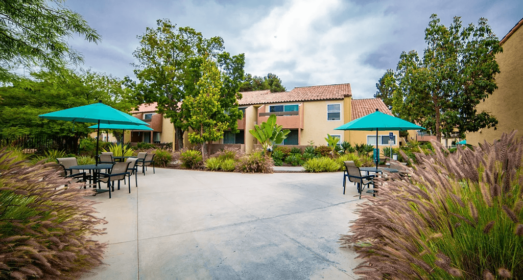 a patio with tables and umbrellas in front of a building