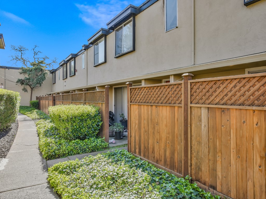 a wooden fence separates a row of houses from a sidewalk