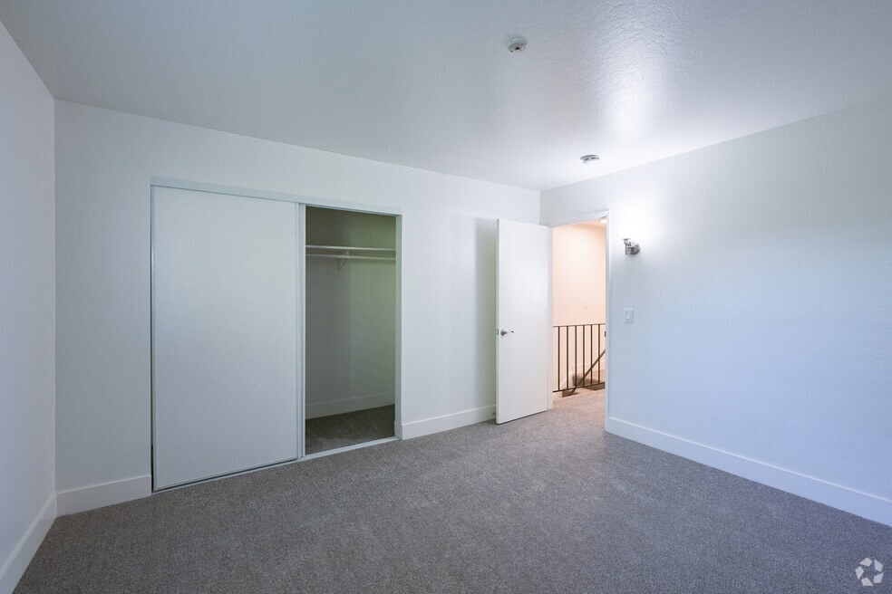 a bedroom with white walls and a closet with mirrored doors