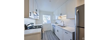 an empty kitchen with white cabinets and stainless steel appliances