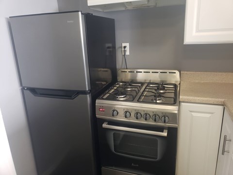 A black refrigerator is next to a stove in a kitchen.