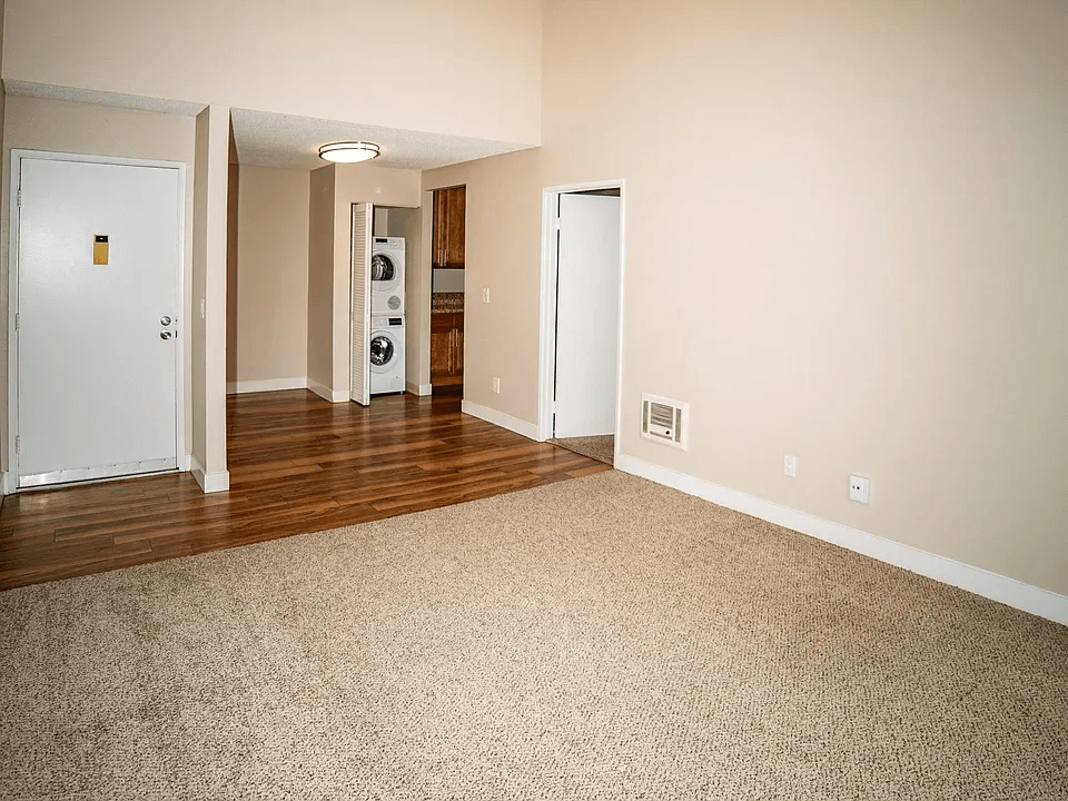 an empty living room with wood floors and white walls