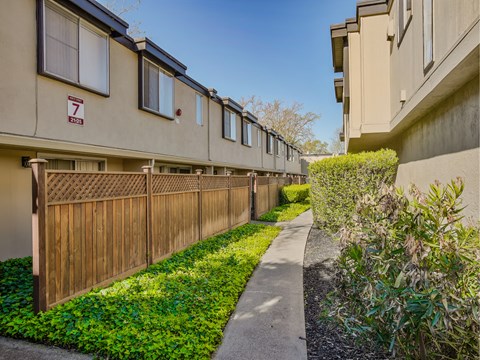 a sidewalk in front of a building with a wooden fence