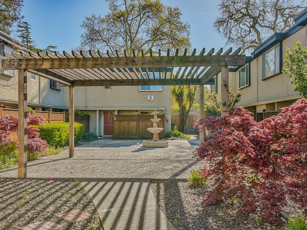a pergola with a fountain in front of a building
