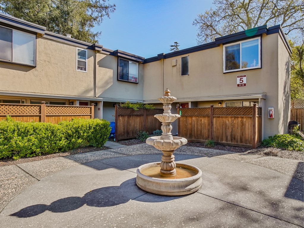 a fountain in the middle of a driveway in front of a house