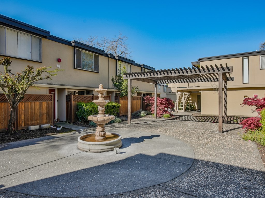 a fountain sits in the middle of a driveway in front of a house