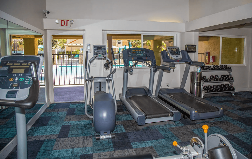 a gym with cardio machines and weights in a building with a pool