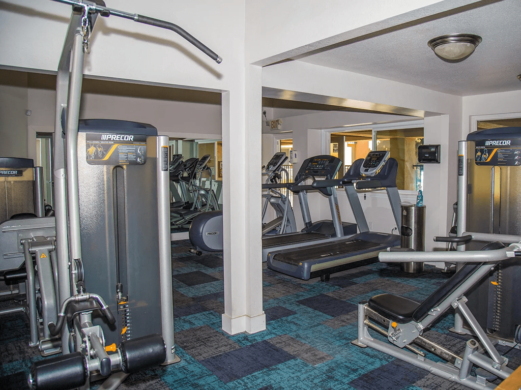 a gym with cardio machines and other equipment in a room