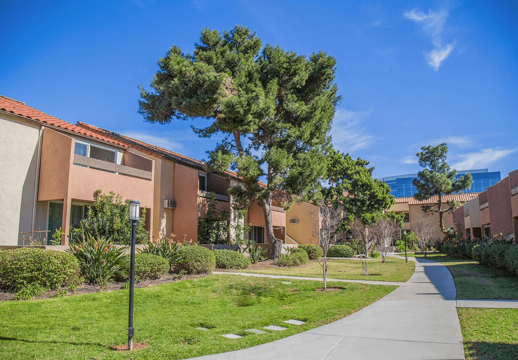 a sidewalk in front of a building with trees and grass