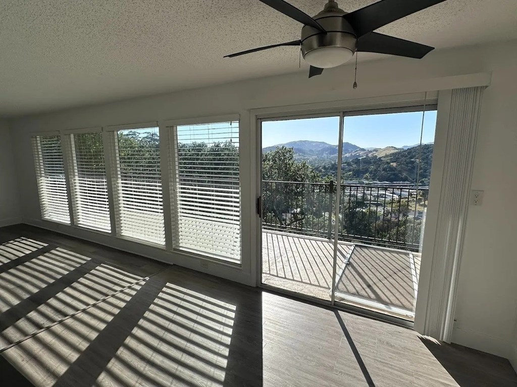 A room with a ceiling fan and a view of the mountains outside.