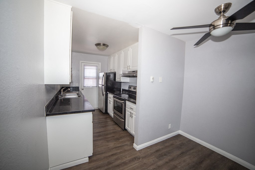 a kitchen with white cabinets and a black counter top